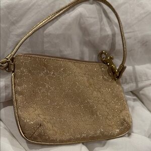 Coach Shimmering Gold Wristlet in a metallic gold finish.